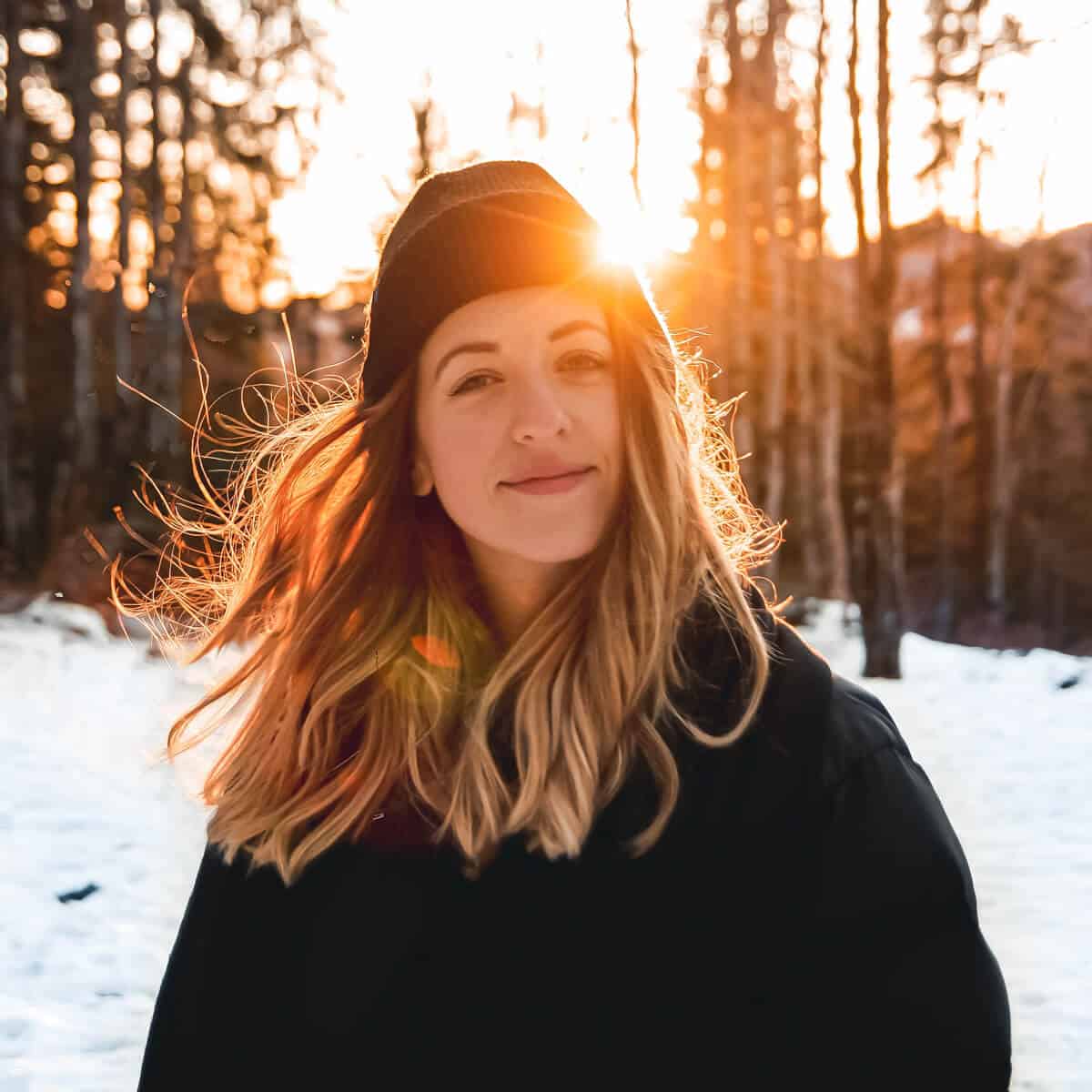 Person standing in the snow with the sun behind.