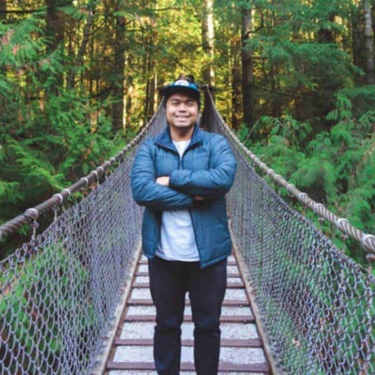 Person standing on a bridge in the forest.