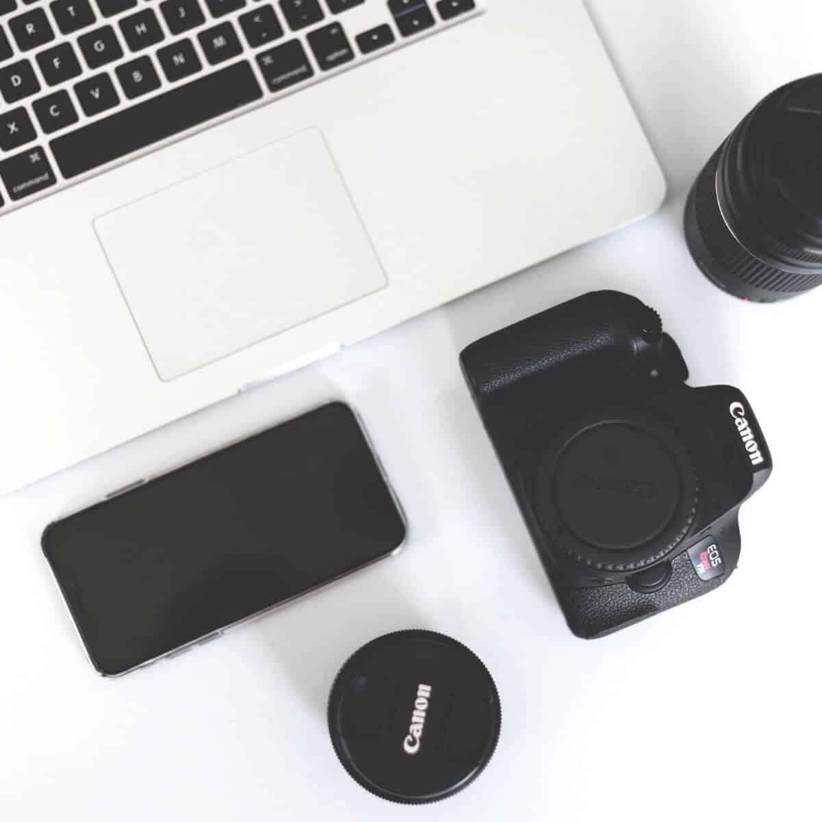 Flatlay of camera, laptop, lenses, and phone.