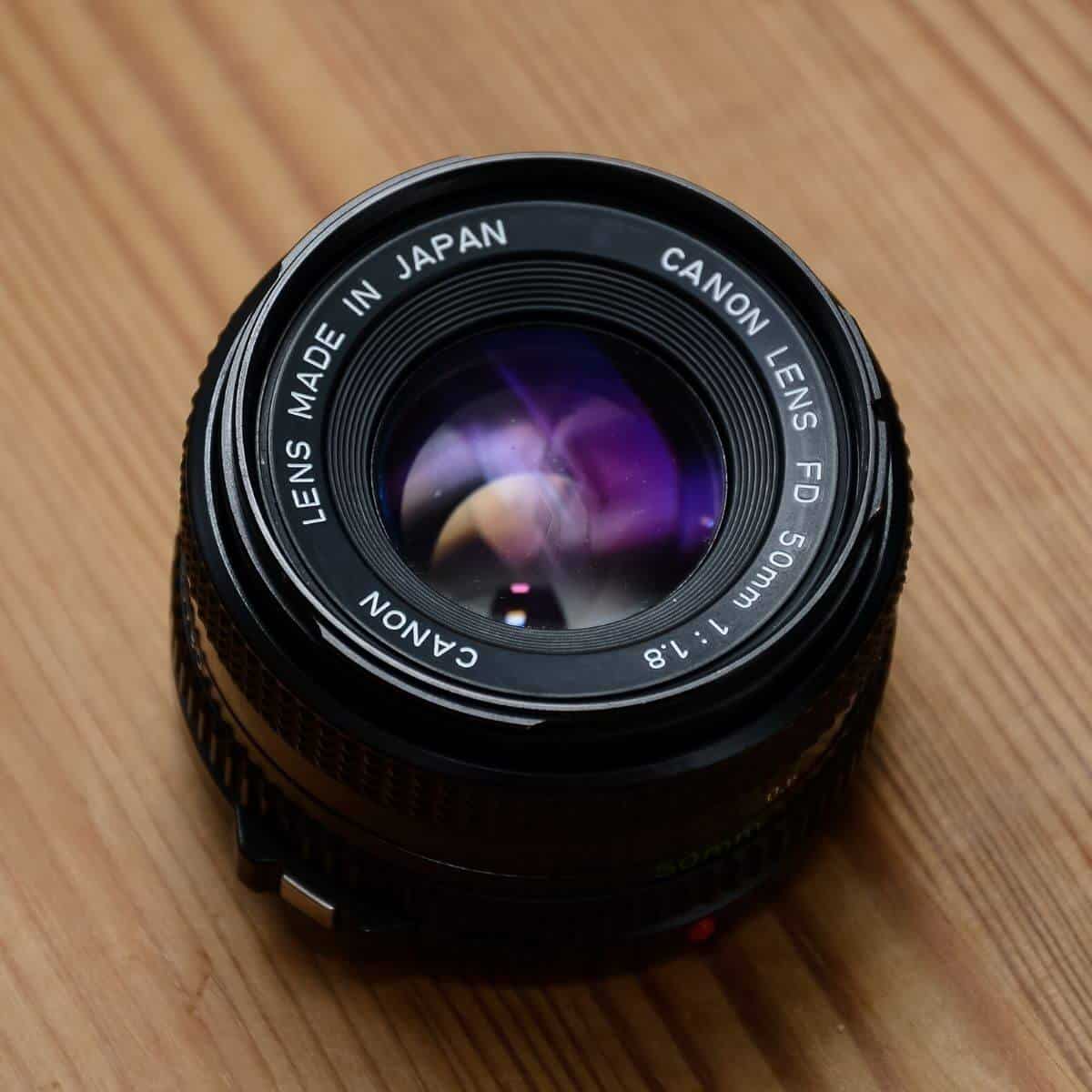 Canon 50mm lens on a wooden table.