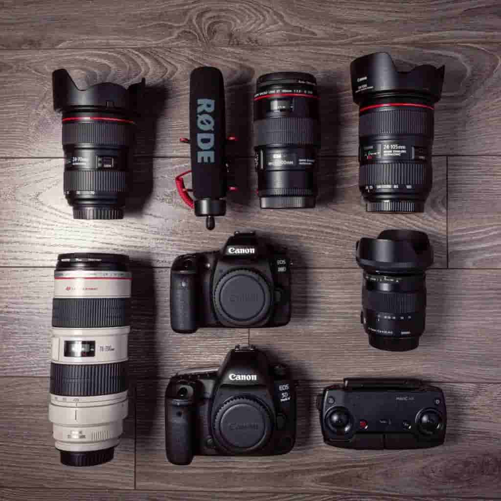 Flatlay of cameras, lenses, microphones, and a remote control.