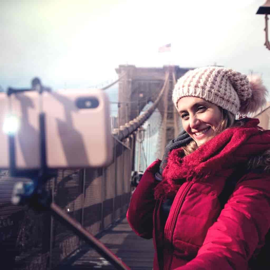 Person on a bridge using a selfie stick to take a self-portrait.
