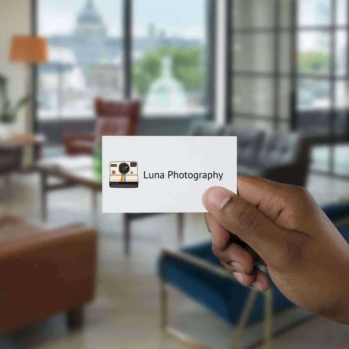 Person's hand holding a photography business card.