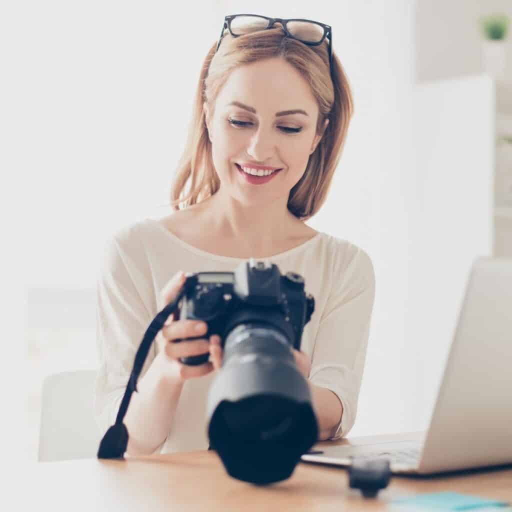 Photographer looking at their camera on a table next to a laptop.