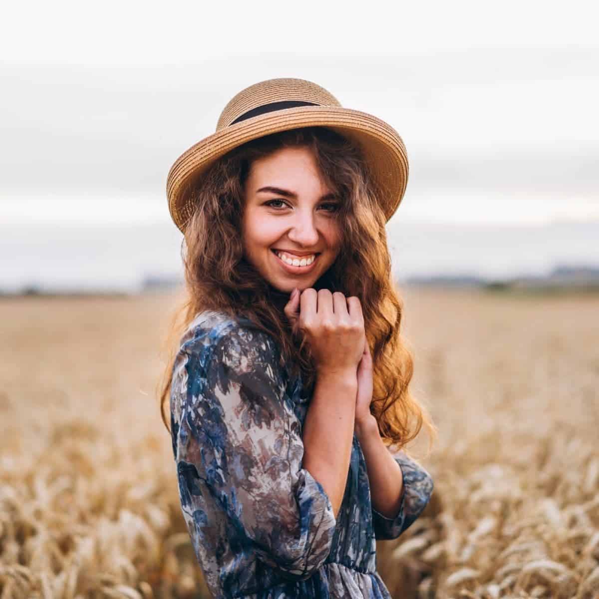 Woman wearing a hat and standing in a field.