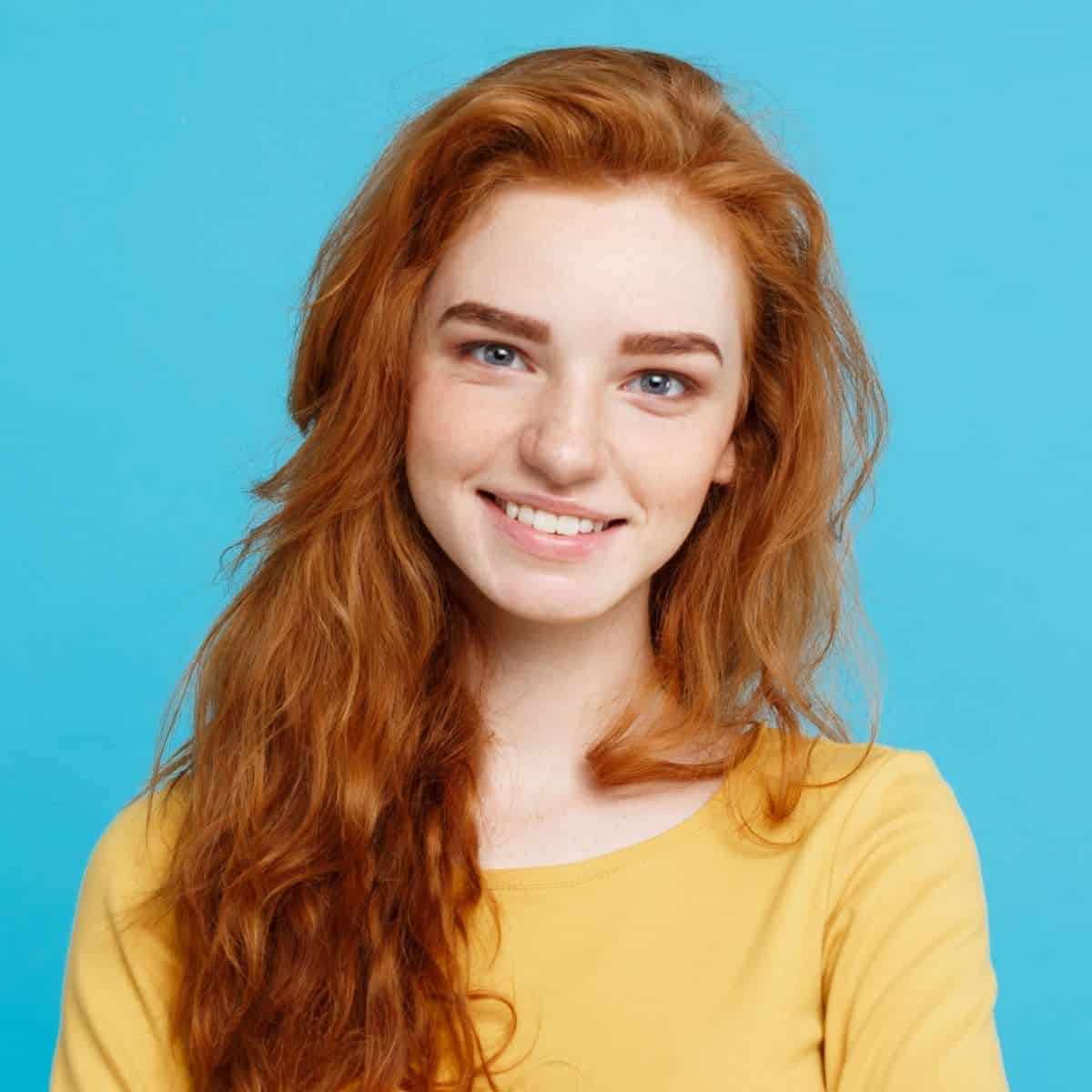 Portrait of a girl with orange hair smiling.