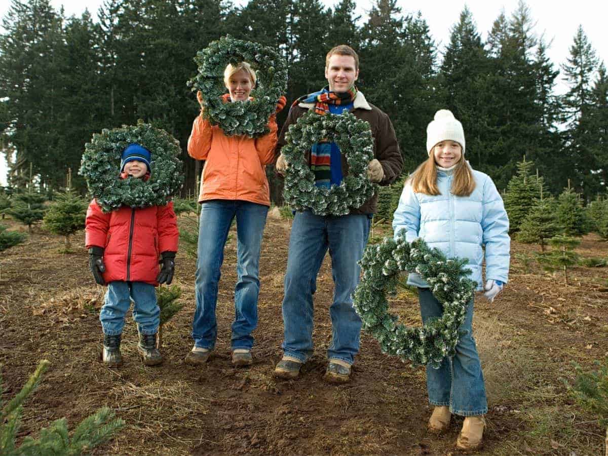 Family at a tree farm holding wreaths.