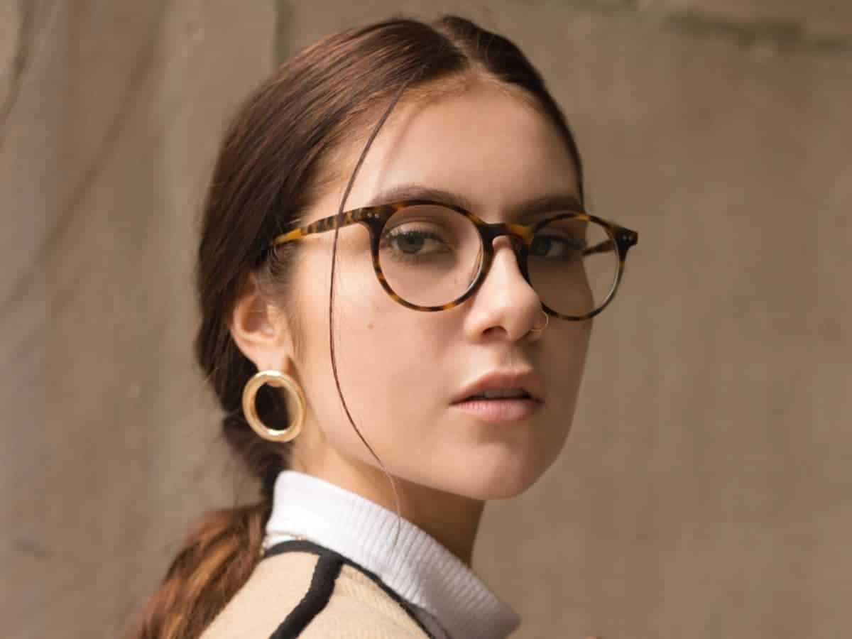 Headshot of a woman with glasses and earrings.