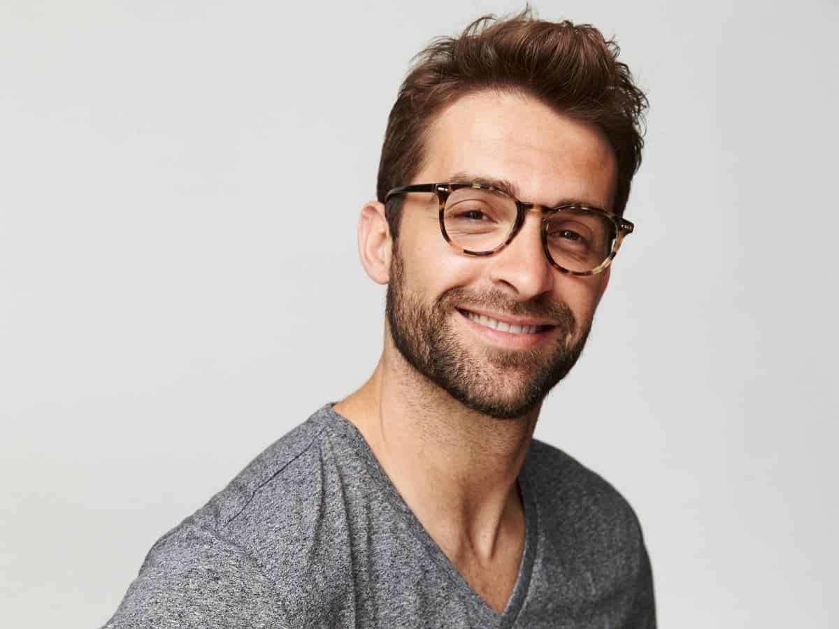 Man with a beard and glasses smiling.