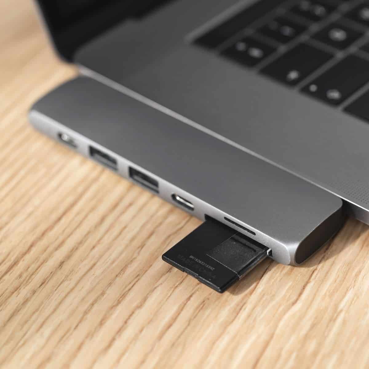 Memory card in a reader attached to a laptop on a table.