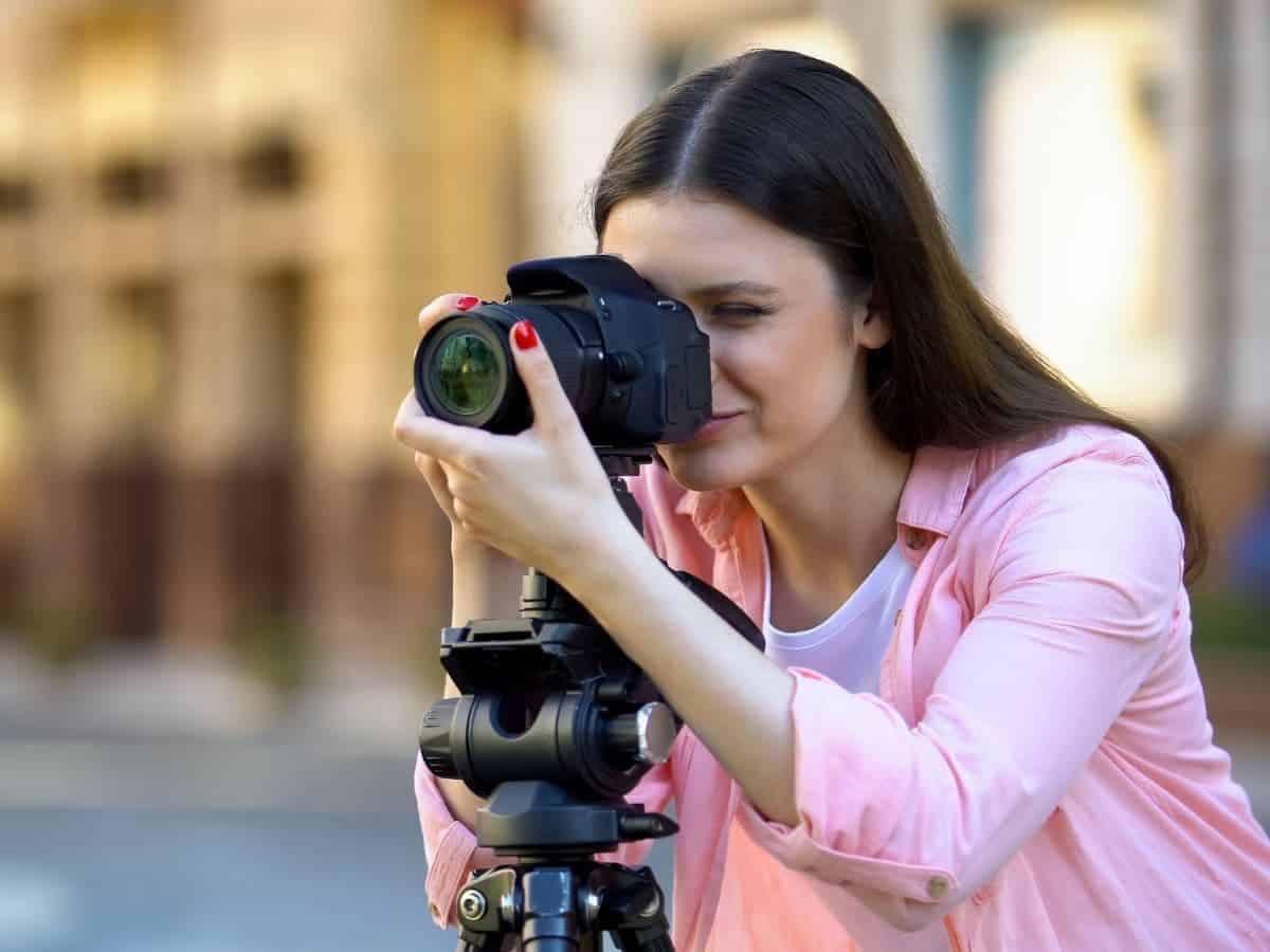 Photographer focusing a camera on a tripod.