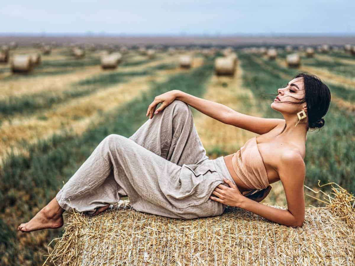 Woman leaning on her arm while laying on hay.