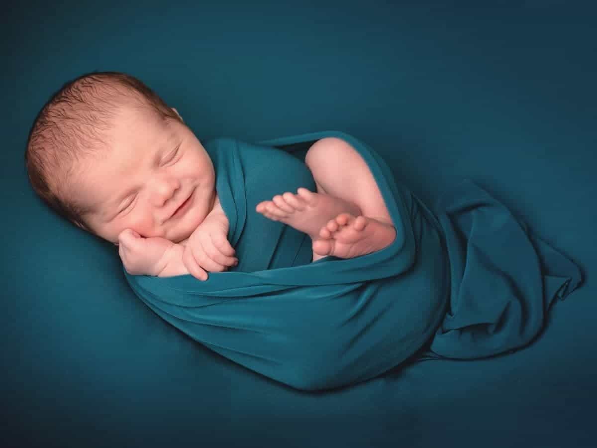 Baby wrapped in a blanket with hands and feet showing.