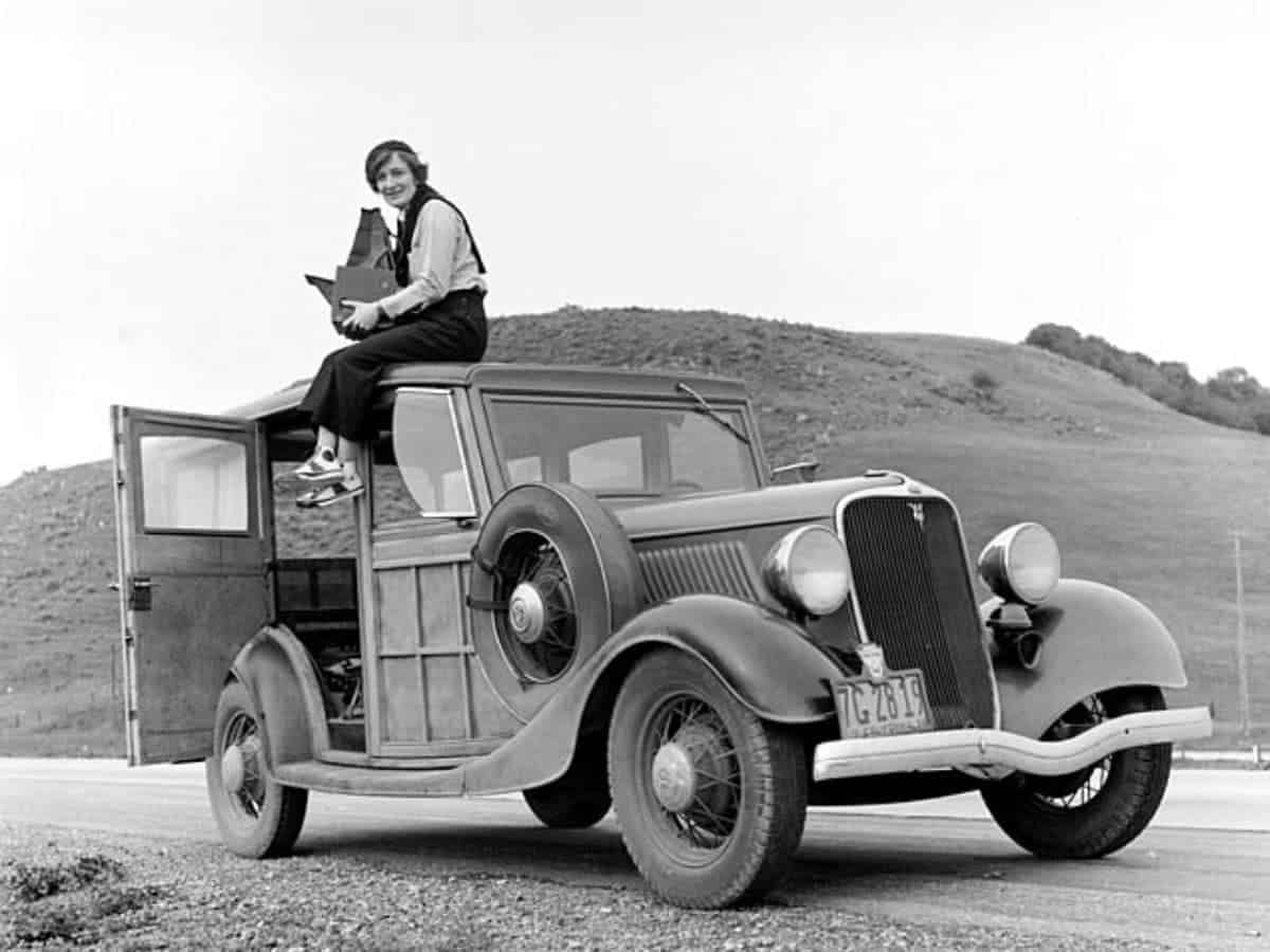 Dorothea Lange sitting on top of a car.