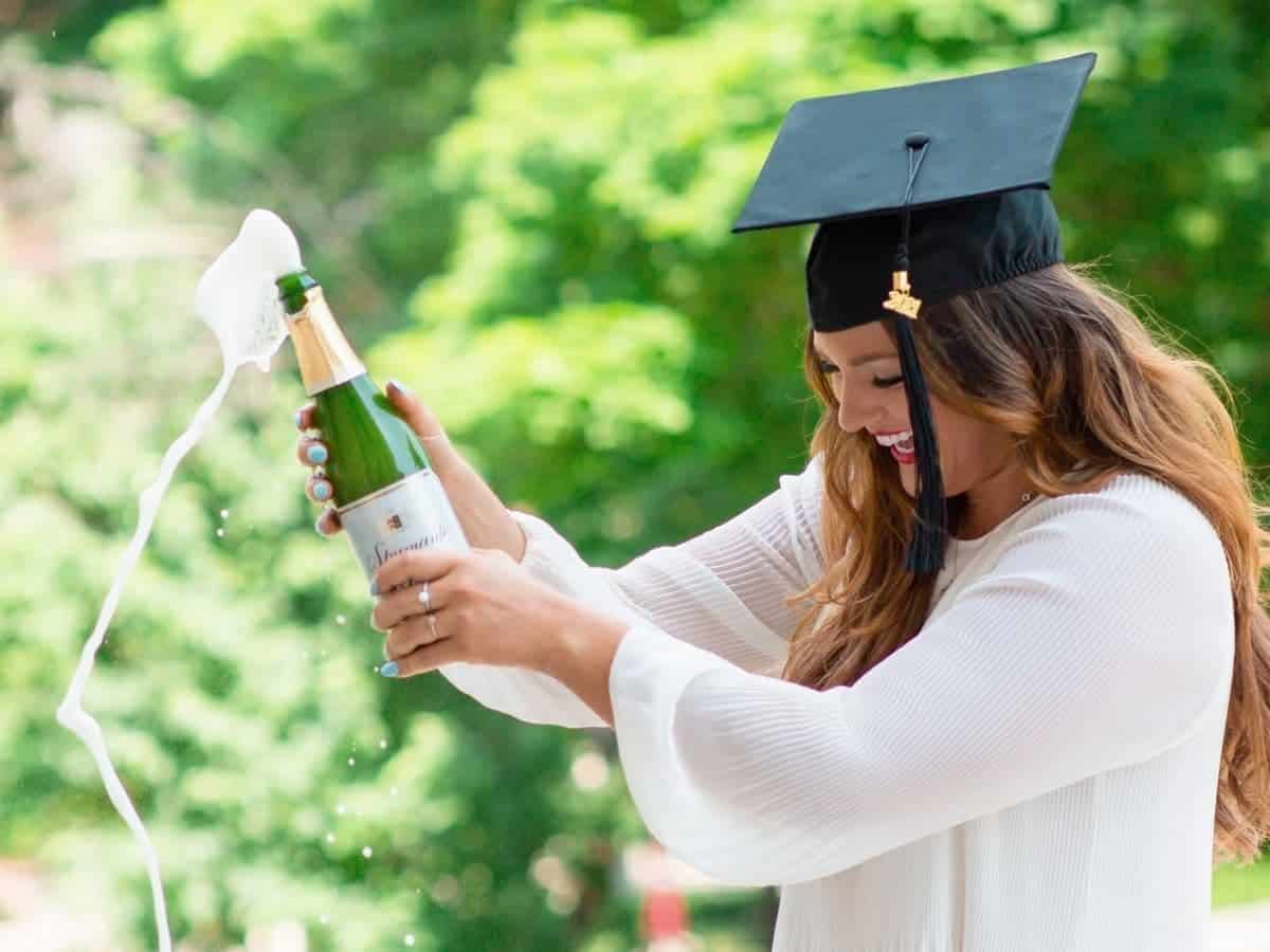 Graduate outdoors spraying champagne.