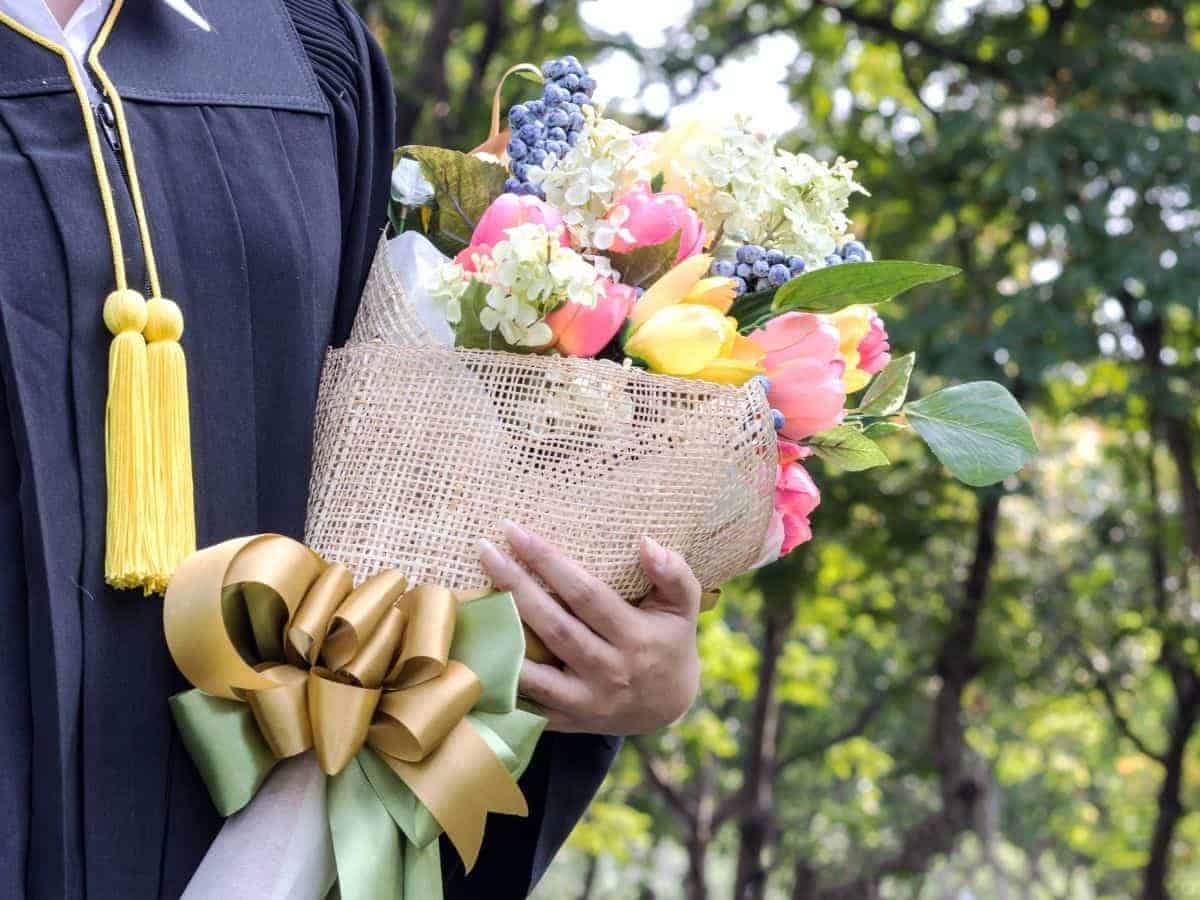 Close-up of a graduate holding flowers.
