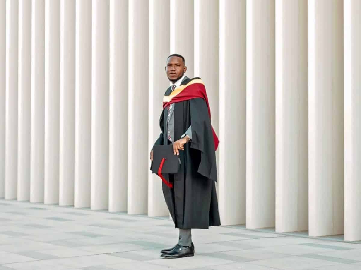 Graduate standing in front of a wall with vertical patterns.