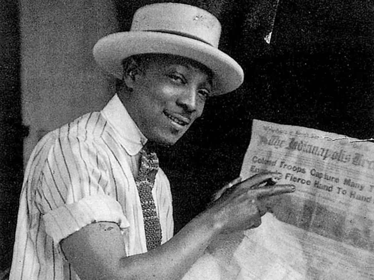 James Van Der Zee wearing a hat and holding a newspaper.