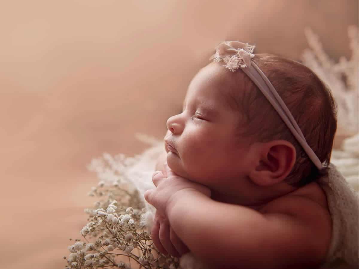Newborn with hands under chin.