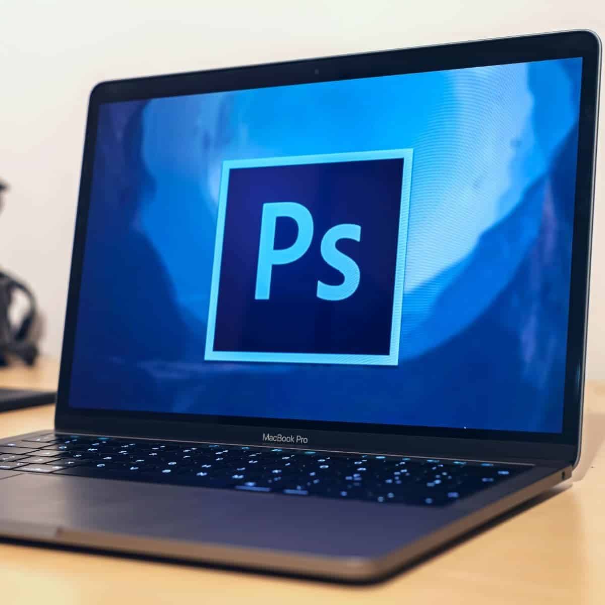 Laptop on a table displaying the Photoshop logo.