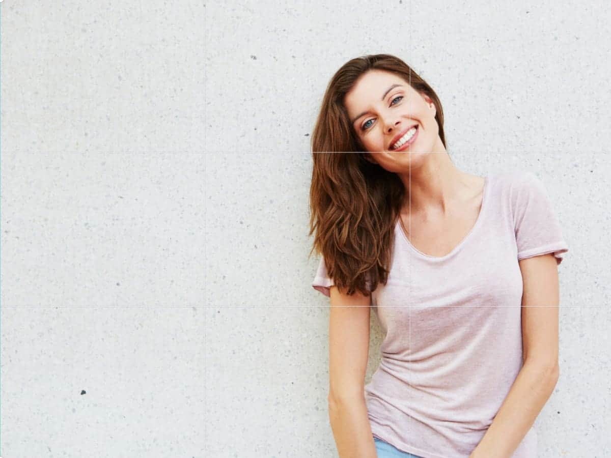 Woman smiling and leaning against a wall.
