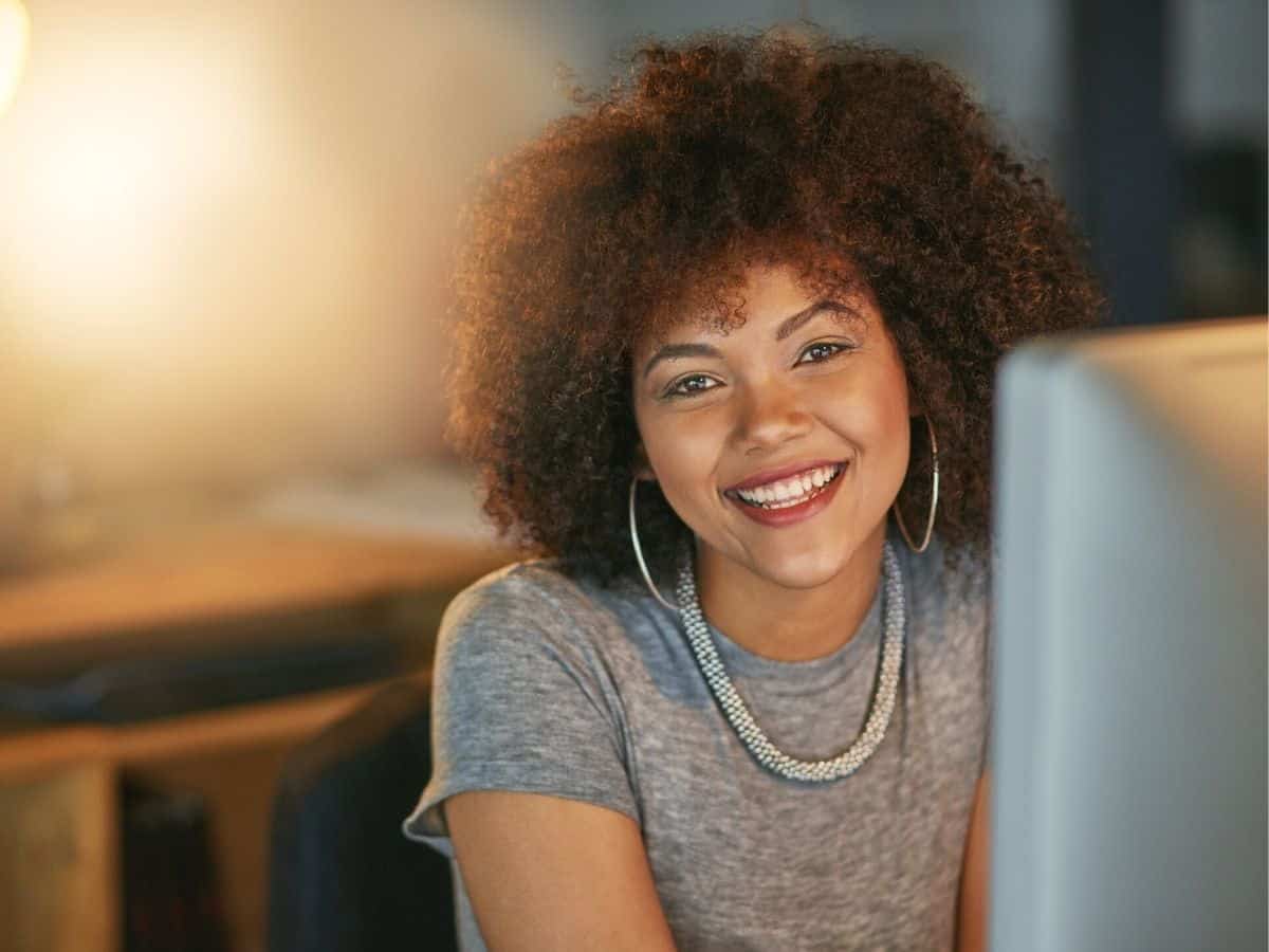 Portrait of a woman smiling behind a computer.