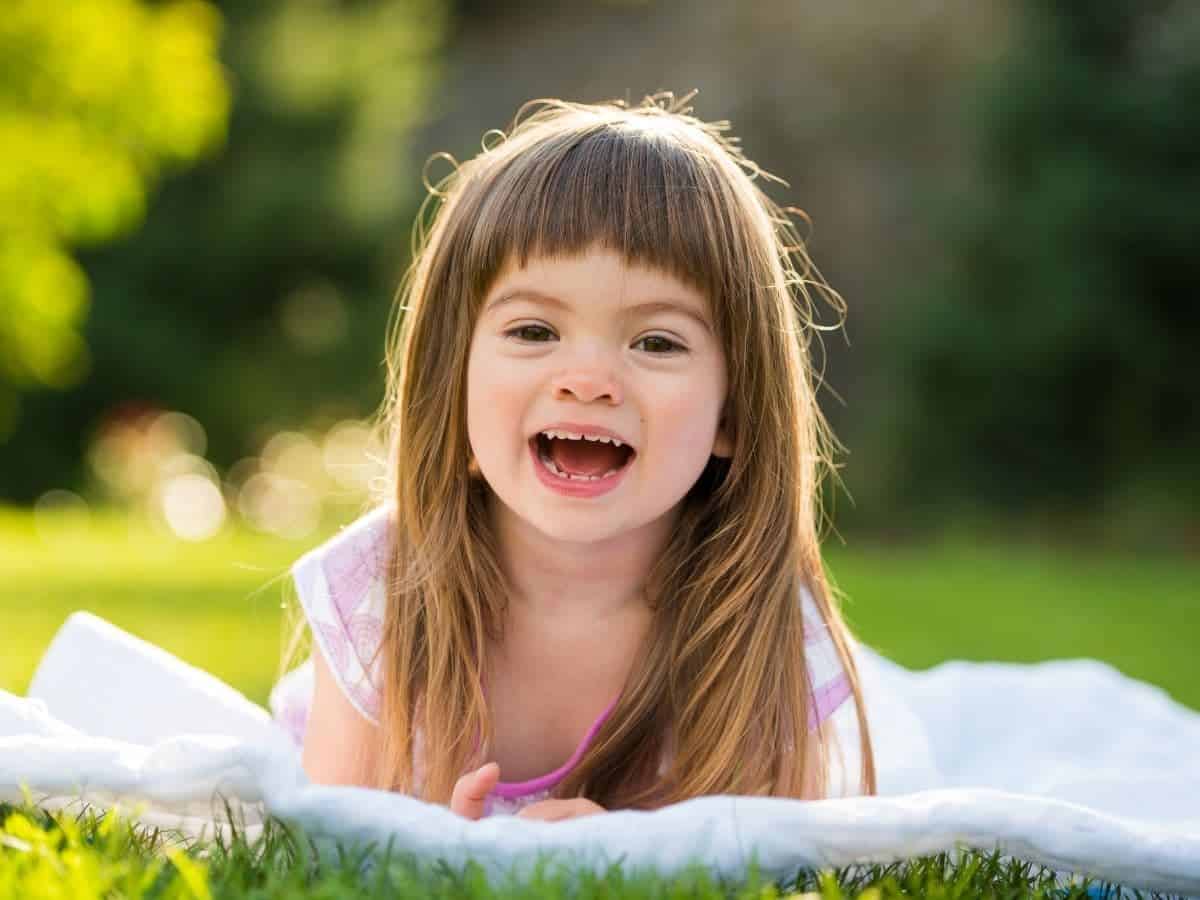 Child laying on grass and laughing.