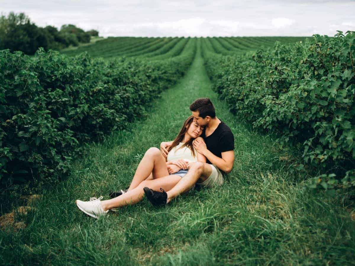Couple sitting and hugging in a grass field.