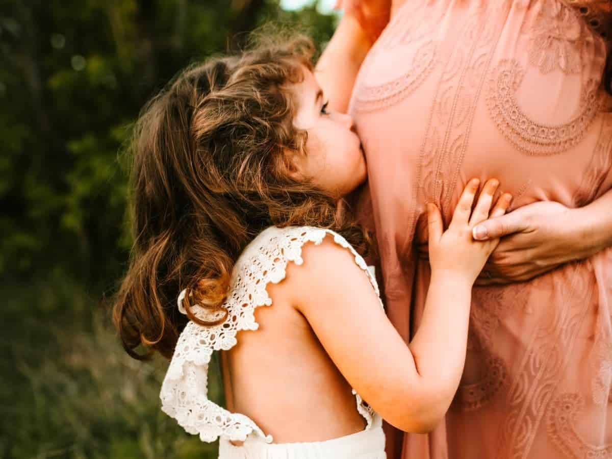 Child kissing pregnant mother's stomach.