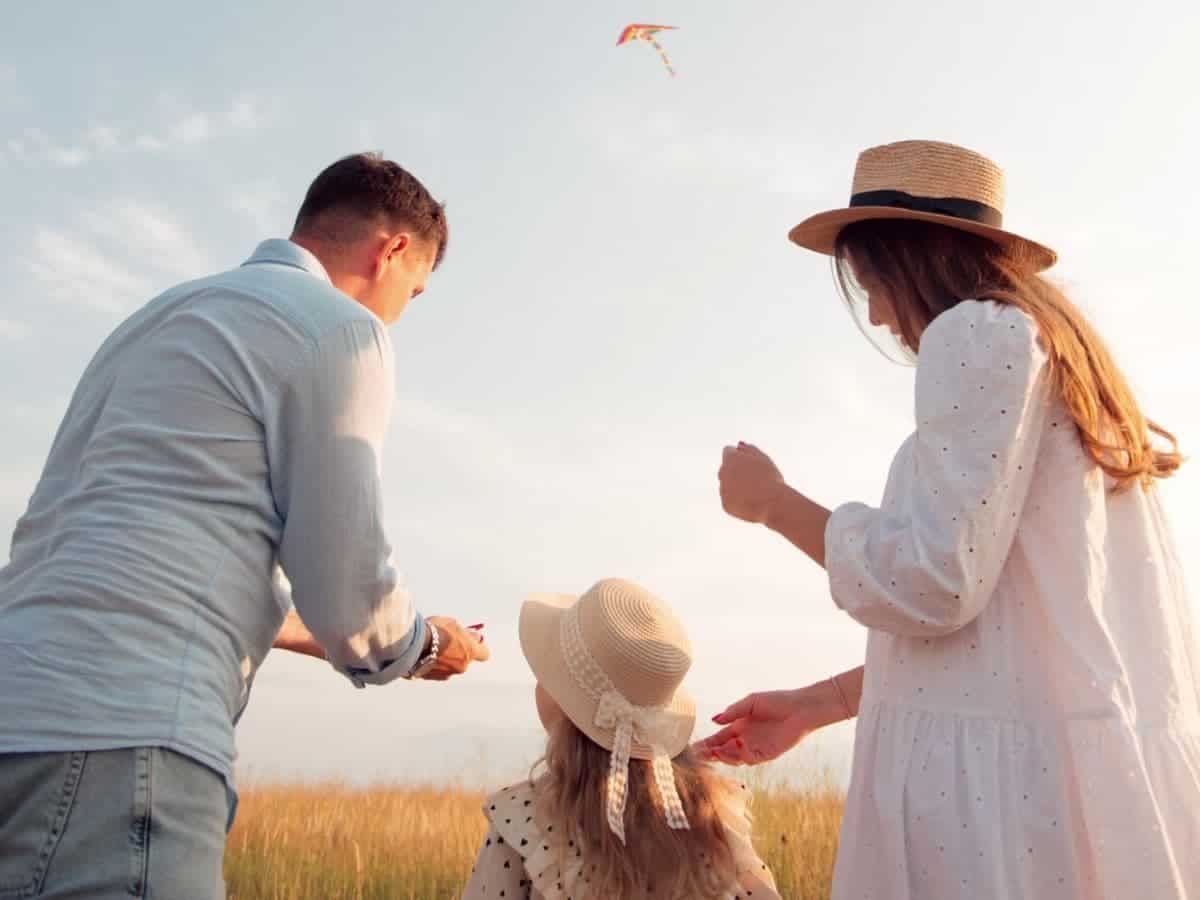 Family flying a kite in a field.