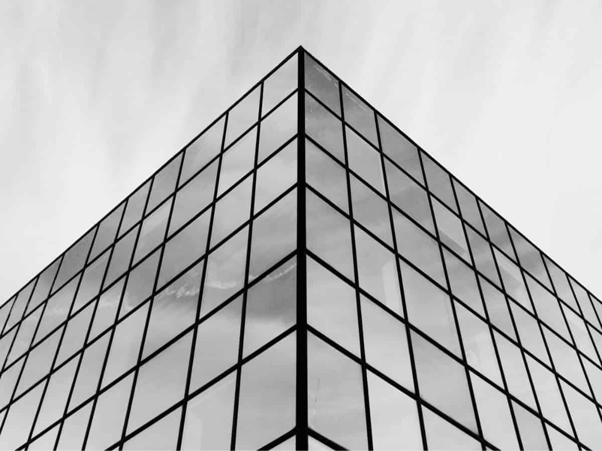 Greyscale of a corner of a glass building.