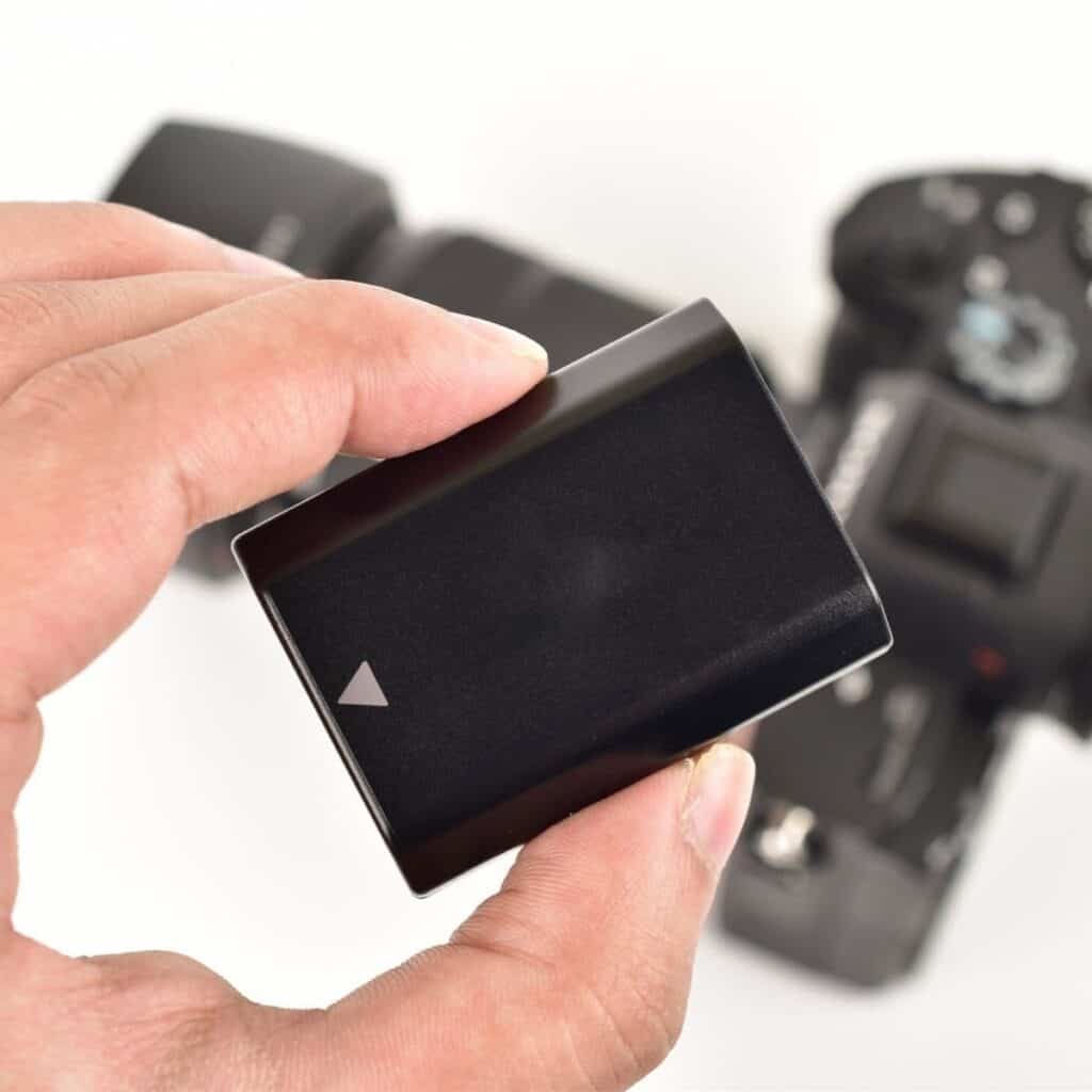 Hand holding a battery over a camera.