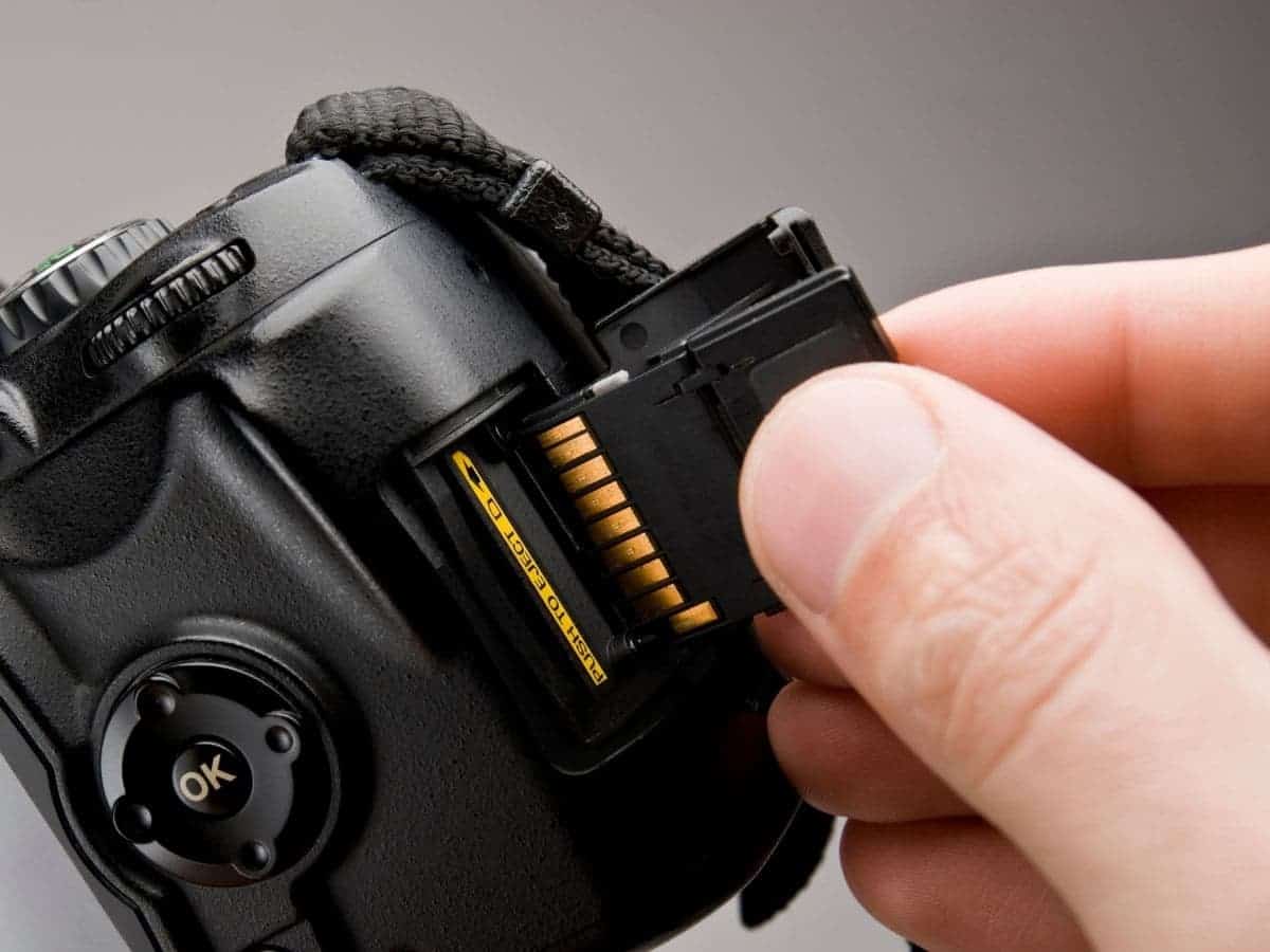 Person inserting a memory card into a camera.