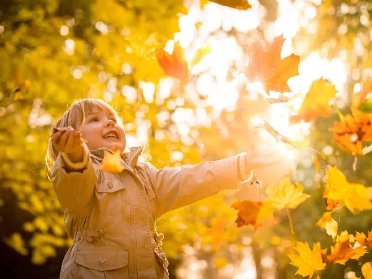 Kid catching leaves and laughing.