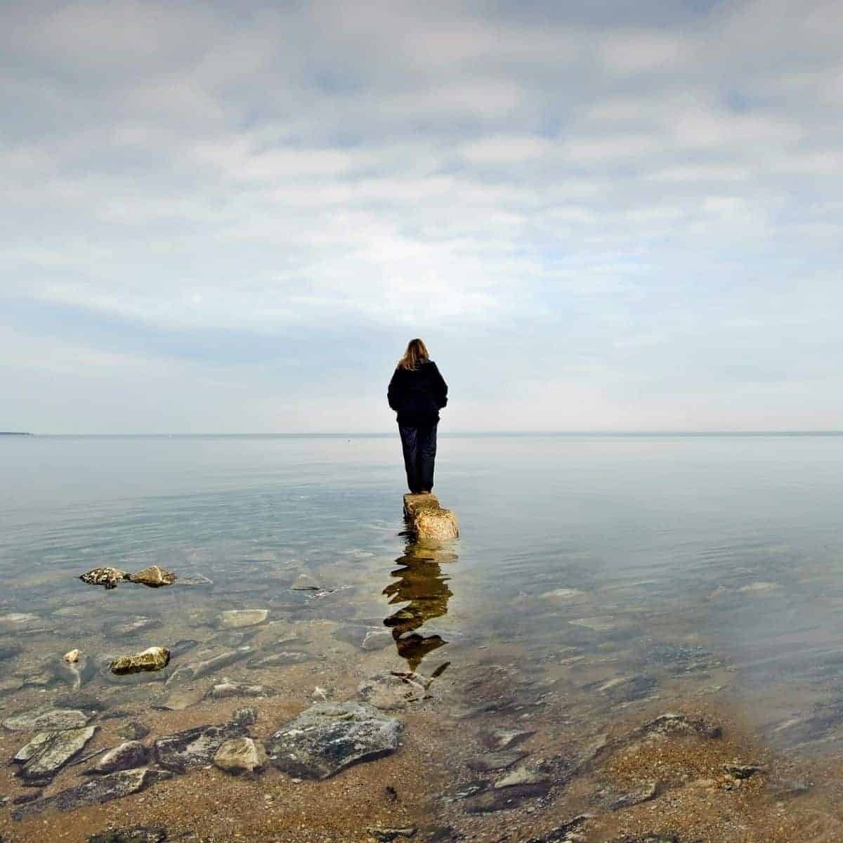 Person standing on a rock in the water.