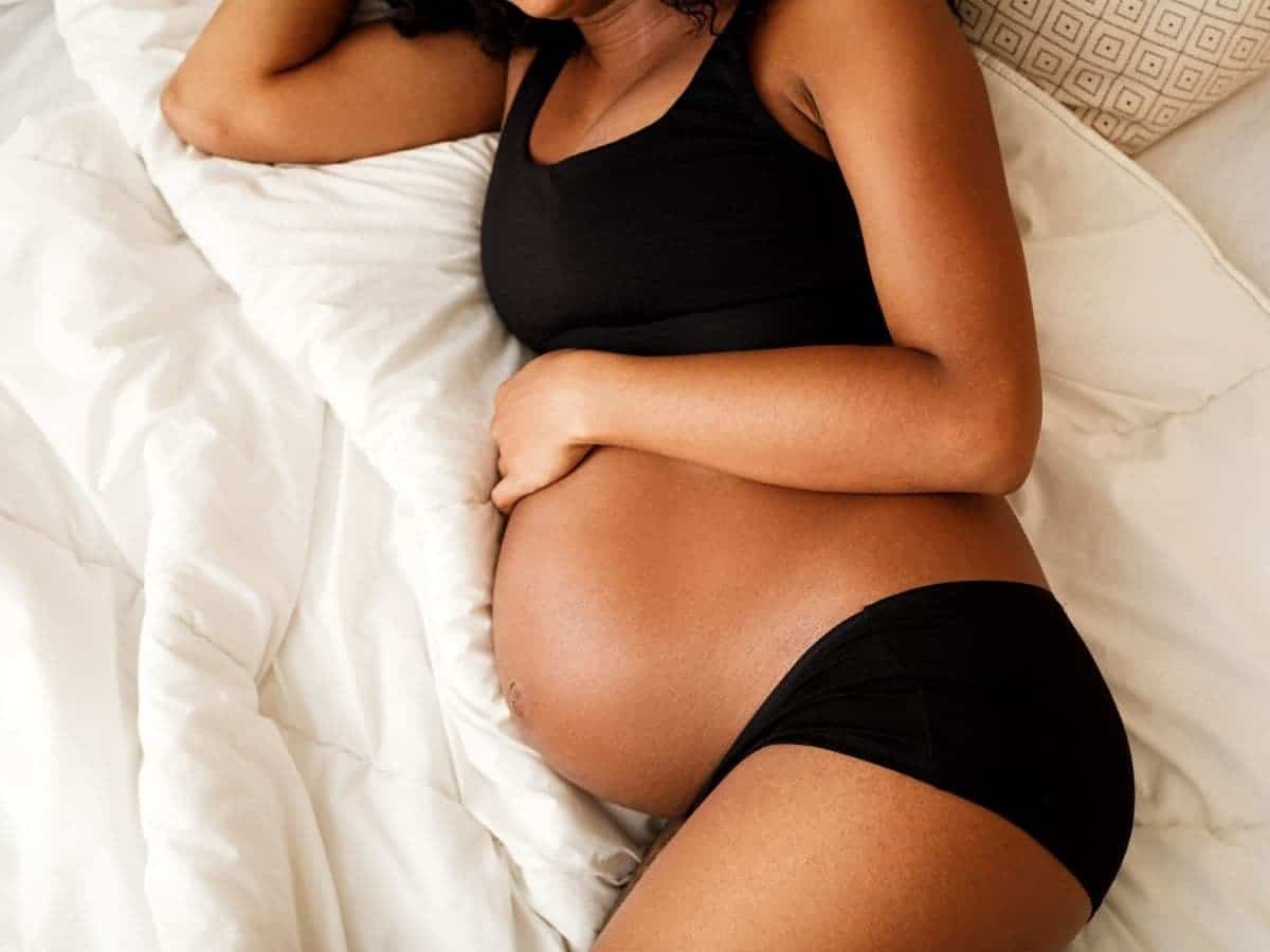 Pregnant woman laying on her side on a bed.