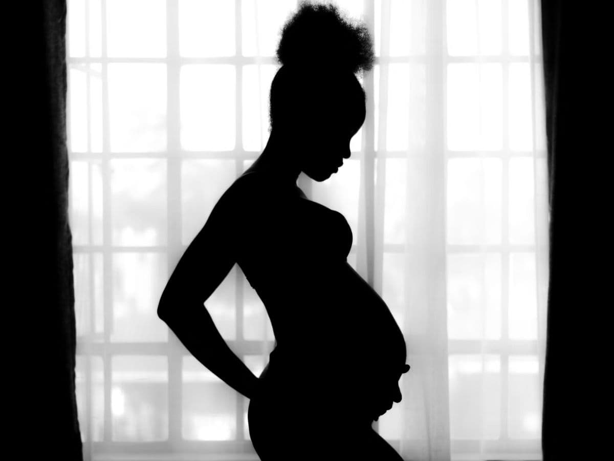 Silhouette of a pregnant woman in front of a window.