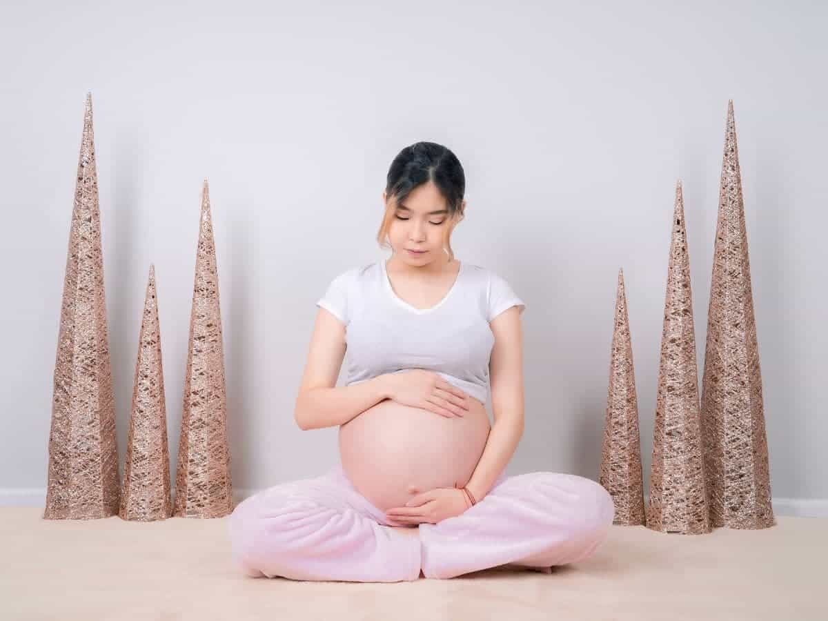 Pregnant woman sitting on the floor in a home with cones on her sides.