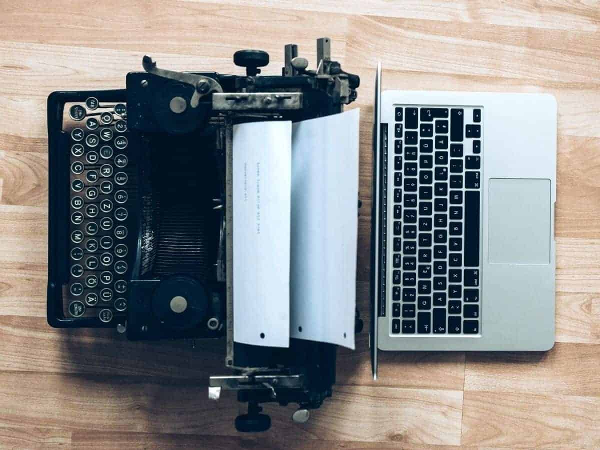Typewriter and laptop on a wooden table.