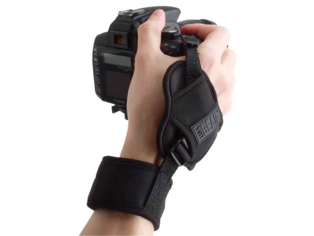 Hand holding a camera with a hand strap.
