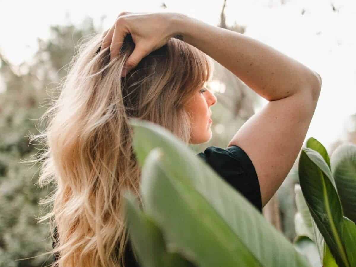 Person grabbing their hair and surrounded by plants.
