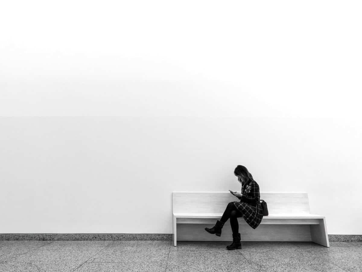 Woman sitting on a bench and looking at her phone.