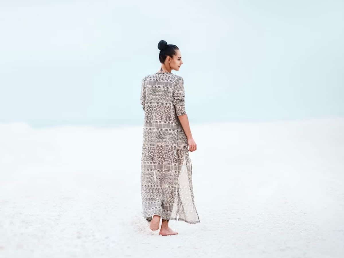 Person wearing a dress and walking on white sand.