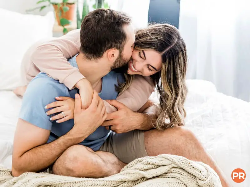 Couple sitting on a bed and laughing.