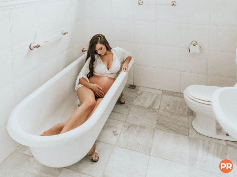 Pregnant woman sitting in a bathtub.