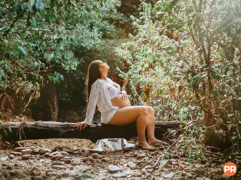 Pregnant woman sitting on a log.