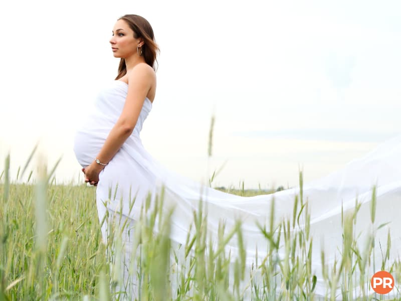Pregnant woman wearing a dress in a field.