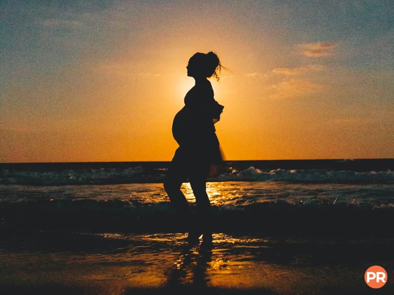 Silhouette of a pregnant woman at the beach during a sunset.