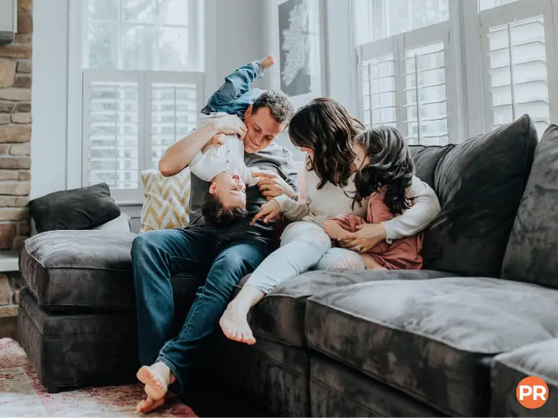 Family on a couch hugging and playing.