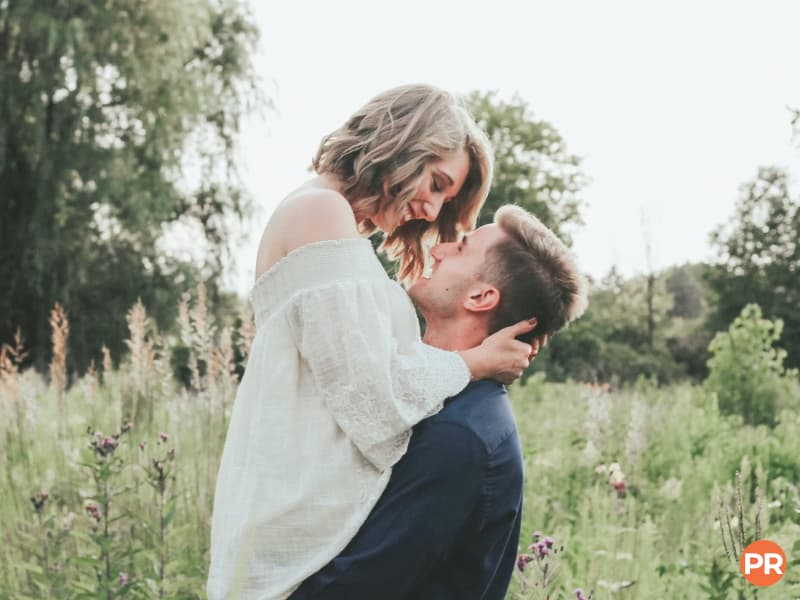 Light and airy photography of a couple hugging in a grass field.